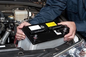 Ein Mechaniker wechselt eine defekte Autobatterie bei einem Auto