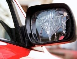 Ein kaputtes Speigelglas eines Außenpiegels bei einem roten Ford Fiesta