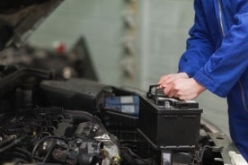 Ein Mechaniker wechselt eine defekte Autobatterie bei einem Auto