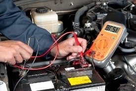 Automechaniker beim Testen der Autobatterie mit einem Testgerät