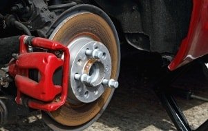 Nahaufnahme der Bremsanlage mit dem roten Bremssatel beim Wechsel