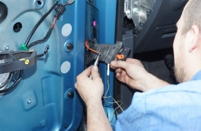 Fachmann bei der Reparatur des elektrischen Fensterhebers eines Autos in der Werkstatt