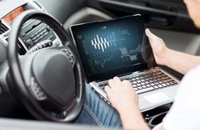 Hauptuntersuchung - Mechaniker überprüft technische Daten im Auto mit Laptop