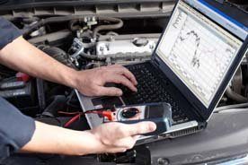 Ein Mechaniker prüft den Volkswagen während einer Inspektion und hat die Leistungswerte auf seinem Laptop