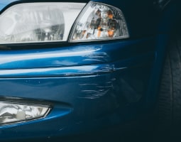 Lackschaden an der Sroßstange vorne bei einem blauen Auto