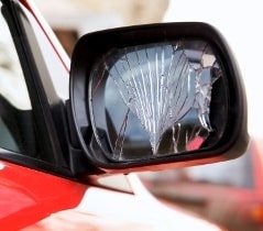 Gerissenes Spiegelglas eines roten Autos 