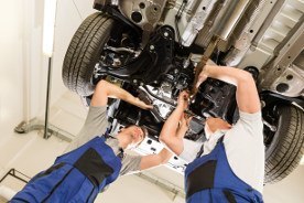 Zwei Kfz-Mechaniker wechseln die Spurstangenköpfe beim Auto in einer Werkstatt